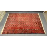 A North West Persian Woollen Rug with an all over design upon a red, blue and cream ground within