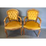 A 20th Century Pair of French Armchairs each with a button upholstered back and padded seat raised