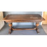 An Oak Draw Leaf Refectory Style Dining Table with a carved frieze raised upon turned baluster