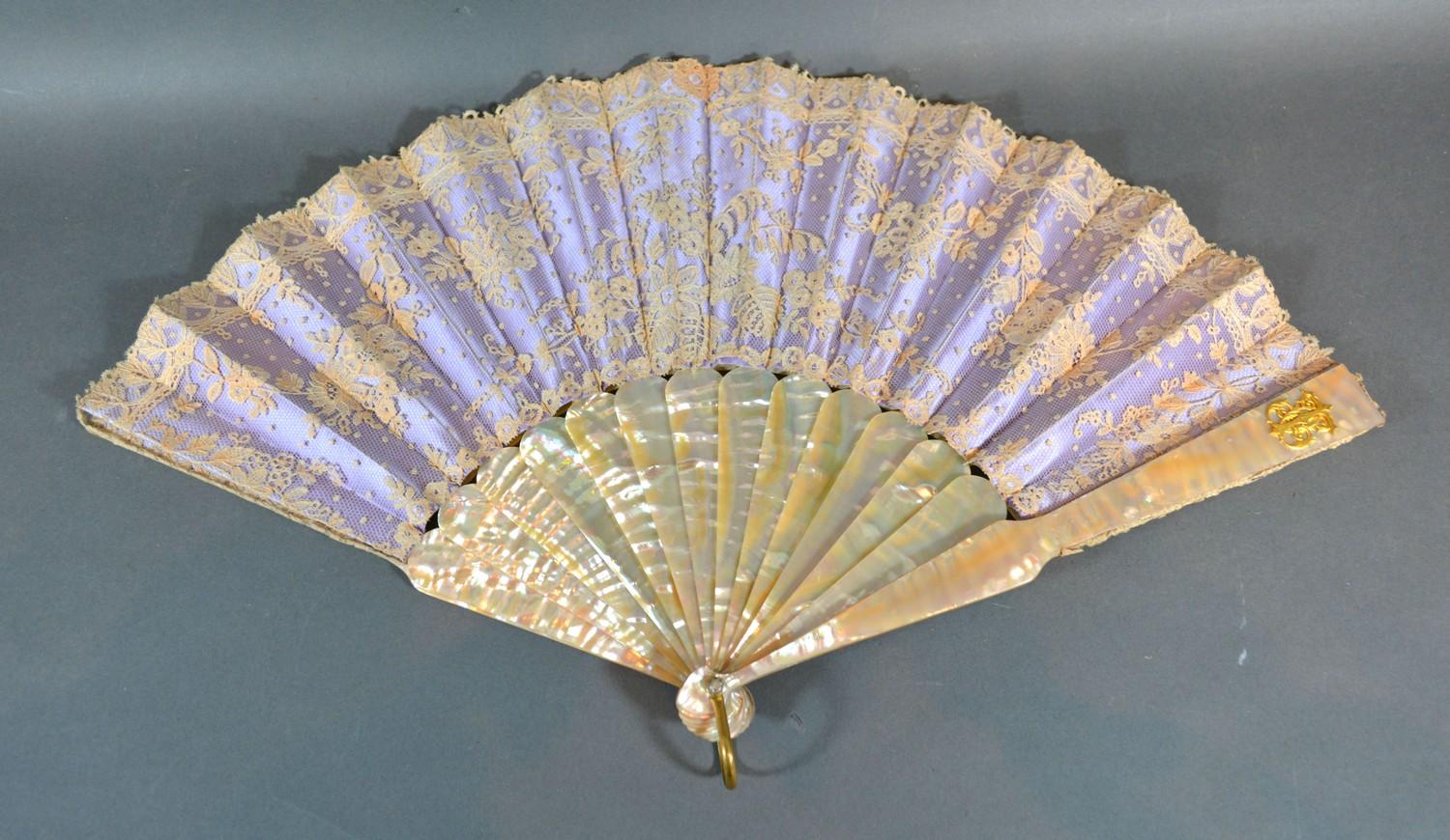 A Lace Fan backed with lilac satin with mother-of-pearl sticks and guards with gilded monogram