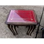 A nest of three side tables, red and gold leather inlaid with glass tops. An attractive set.