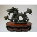 ORIENTAL METALWARE, a bronze miniature figure of a fabulous dragon on carved hardwood stand