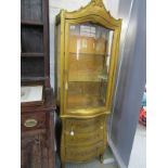 GILT VITRINE, serpentine fronted triple drawer base with glass panel door and gilt cresting, 68"