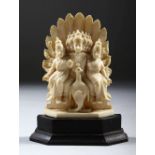 A SMALL INDIAN CARVED IVORY GODDESS GROUP, on a wooden base, 11cm high.