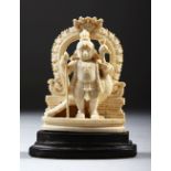 A SMALL CARVED INDIAN IVORY OF A FIGURE WITH A PEACOCK, on a wooden base, 9cm high.