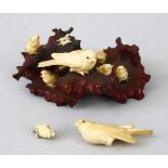 A JAPANESE MEIJI PERIOD CARVED WOOD AND IVORY BIRD OKIMONO GROUP, the carved stylized timber outcrop