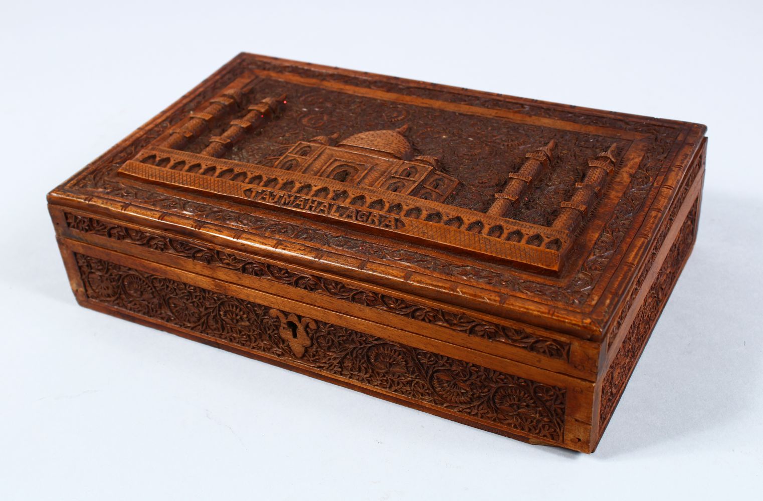 A GOOD INDIAN CARVED HARDWOOD LIDDED BOX, carved in relief to depict the scenes of a temple