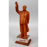 A 20TH CENTURY CHINESE CARVED HARDWOOD FIGURE OF MAO ZEDONG, stood with his hand aloft, upon a glass