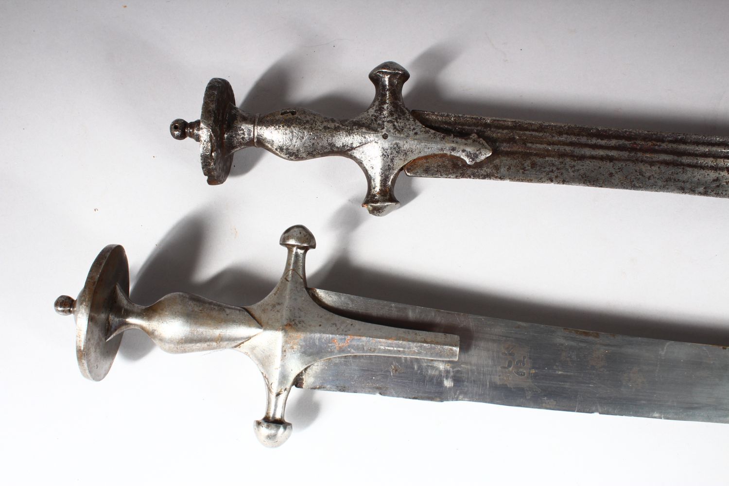 A 19TH CENTURY INDIAN TULWAR, with steel hilt and leather scabbard ...