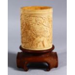 A 19TH CENTURY CHINESE CANTON CARVED IVORY CYLINDRICAL BRUSH POT & STAND, the ivory pot carved to