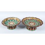 TWO SIMILAR INDIAN POTTERY TAZZAS, hand painted with a floral design, 20.5cm and 25cm diameter.