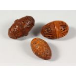 THREE PIERCED AND CARVED COQUILLA NUTS.