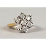 A 9CT GOLD SEVEN STONE DIAMOND DAISY RING.