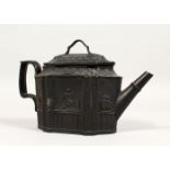 A BLACK BASALT SHAPED TEAPOT AND COVER with classical panels. 8ins long.