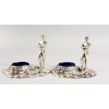 A PAIR OF TABLE SALTS, modelled as early footballing figures. 5.25ins wide.