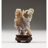 AN UNUSUAL CHINESE CARVED OPAL FIGURE, of a woman holding flowers, on a wood base. 3ins high.