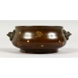 A CIRCULAR BRONZE CENSER, with gold splash decoration and mask handles. 6ins wide.