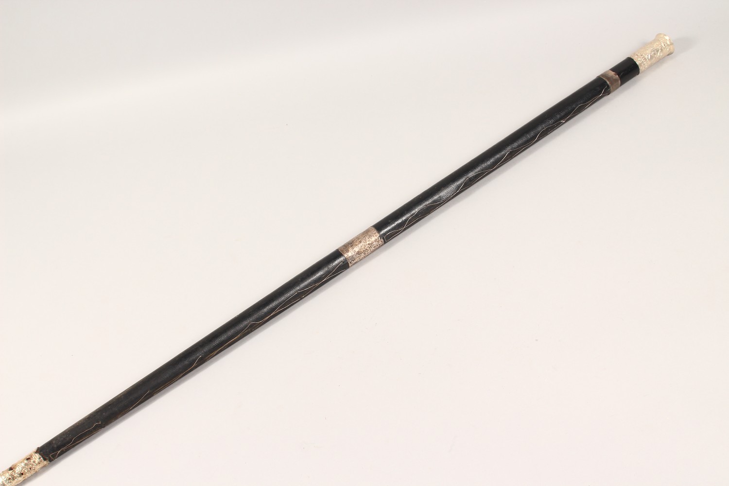 A BLACK LEATHER COVERED WALKING STICK, with eastern white metal mounts. 36ins long. - Image 11 of 11