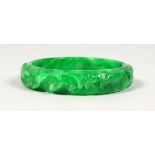 A CARVED GREEN JADE BANGLE. 3ins diameter.