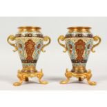 A GOOD PAIR OF 19TH CENTURY GILT METAL AND CLOISONNE TWO-HANDLED URNS, on gilt stands. 5ins high.