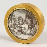 A GILT METAL CIRCULAR BOX, the silvered cover engraved with a figural scene. 4ins diameter.