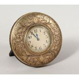 AN ENGRAVED CIRCULAR TRAVELLING CLOCK. 3.5ins diameter.