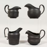 FOUR VARIOUS BLACK BASALT MILK JUGS.