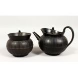 A WEDGWOOD BLACK BASALT CIRCULAR TEAPOT AND COVER and MATCHING SUGAR BOWL AND COVER, the covers with