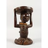 A TRIBAL CARVED WOOD FIGURAL HEAD REST, carved as a kneeling woman, a child on her back. 7.5ins