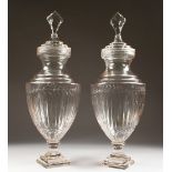 A LARGE PAIR OF CUT GLASS PEDESTAL URNS AND COVERS. 2ft 4ins high.