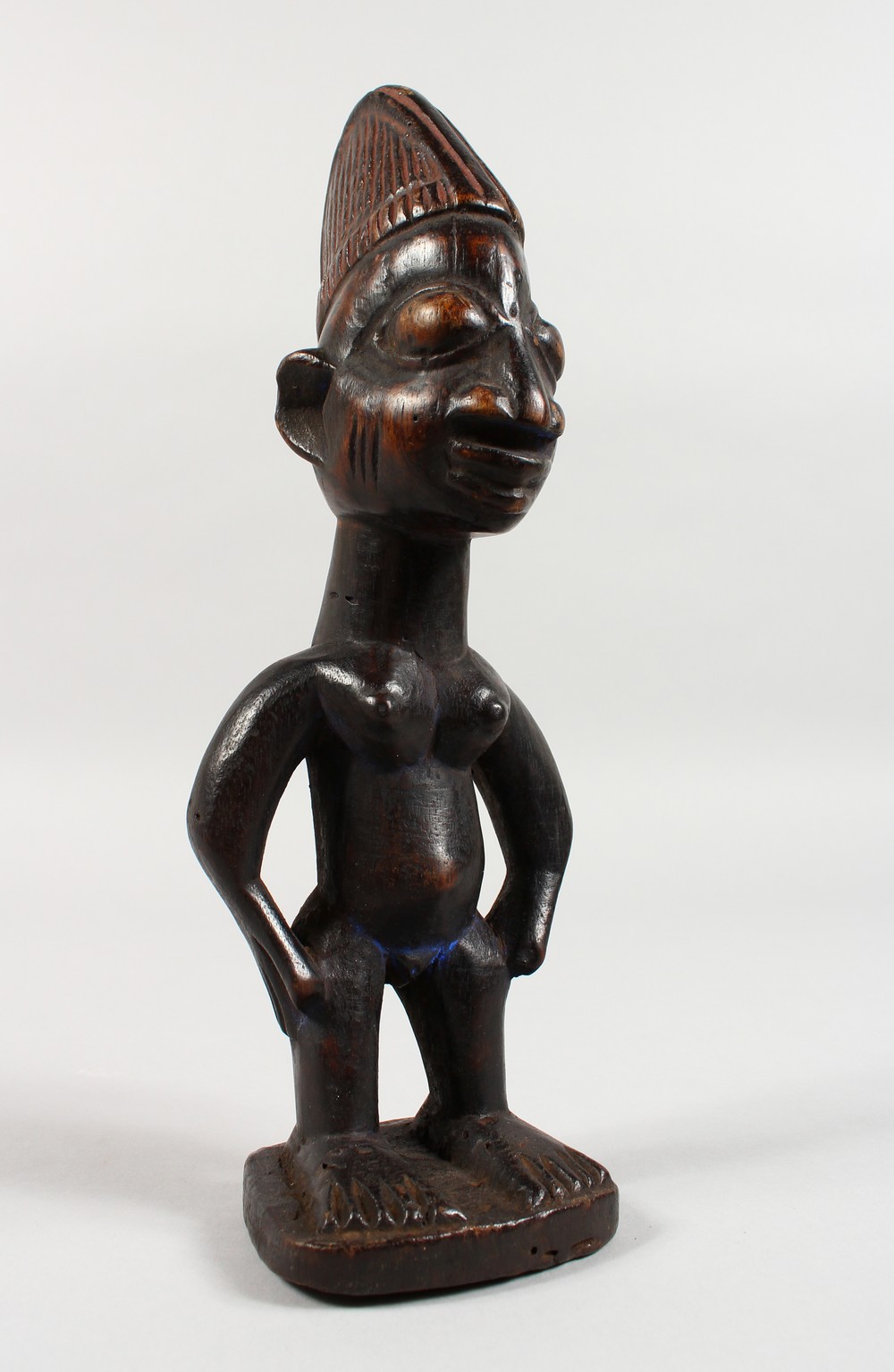 AN YORUBA TRIBE CARVED WOOD STANDING FEMALE FIGURE, with traces of original pigment. 11ins high.