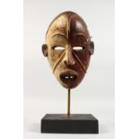 A CARVED AND PAINTED WOOD TRIBAL MASK, on later stand. Mask: 10.5ins high.