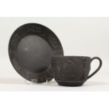 A WEDGWOOD BLACK BASALT TEA CUP AND SAUCER, classical design. Impressed WEDGWOOD, MADE IN ENGLAND.