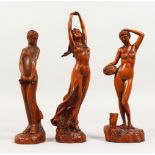 A SET OF THREE CARVED WOOD STANDING FEMALE FIGURES. 8ins and 9.25ins high.