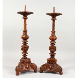 A PAIR OF CONTINENTAL CARVED OAK PRICKET STYLE CANDLESTICKS, on three legs with carved feet. 22ins