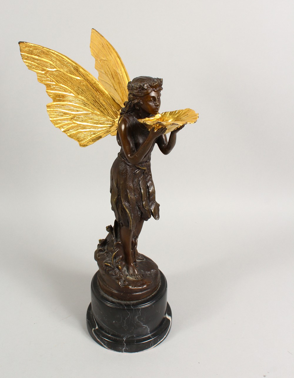 A BRONZE FIGURE OF A FAIRY, 20TH CENTURY, standing holding a shell in her hands, on a marble base.