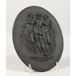 A WEDGWOOD BLACK BASALT OVAL PLAQUE, three classical ladies. Impressed WEDGWOOD. 8.5ins x 6.5ins.