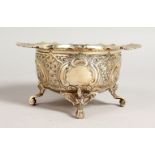 A VICTORIAN TWO-HANDLED SUGAR BASIN, with repousse decoration, on four curving legs. Sheffield 1891.