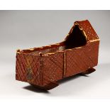 AN UNUSUAL MOULDED TERRACOTTA MODEL OF A CRADLE, with brown slip decoration. 18ins long.