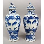 A PAIR OF 19TH CENTURY CHINESE BLUE & WHITE KANGXI STYLE PORCELAIN VASES & COVERS, the body of the