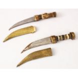 TWO EARLY SYRIAN HORN HANDLE DAGGERS, with gilded sheaths and decorated blades, 27cm long each.