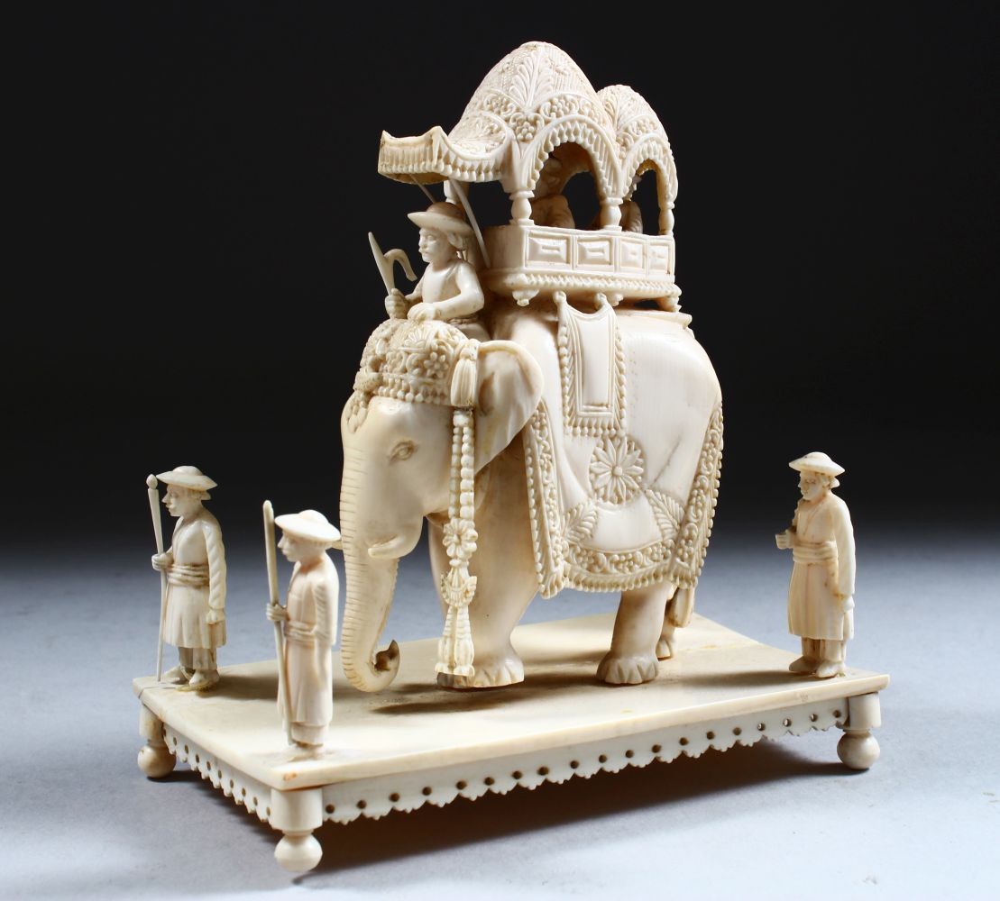 A 19TH CENTURY INDIAN CARVED IVORY FIGURE OF AN ELEPHANT AND ATTENDANTS, in a striding position with