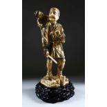 A JAPANESE MEIJI PERIOD CARVED IVORY OKIMONO GROUP, the figure carved to depict a forest man holding