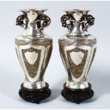 A PAIR OF CHINESE SILVER & SILVER GILT VASES ON HARDWOOD STANDS, the vases each with panels
