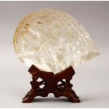 A CHINESE 20TH CENTURY CARVED MOTHER OF PEARL SHELL & STAND, the shell carved to depict scenes of
