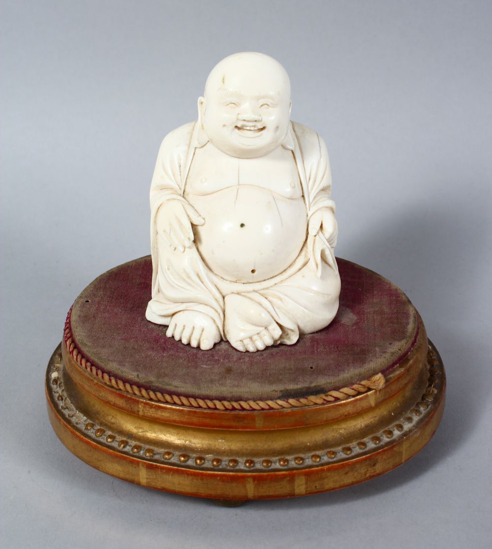 A 19TH CENTURY CHINESE CARVED IVORY BUDDHA ON STAND, the buddha seated upon a later french wooden