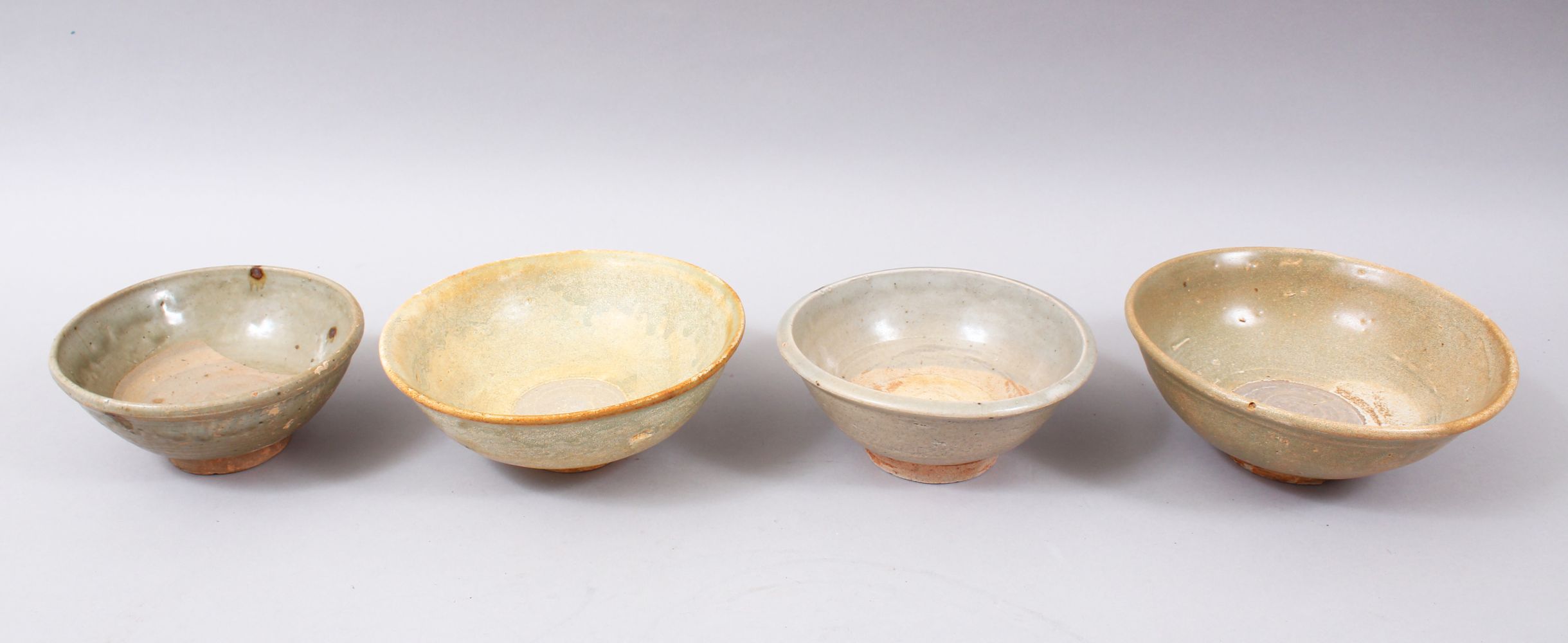 FOUR EARLY CHINESE POTTERY GLAZED BOWLS, some glazed, some partially glazed, various sized but