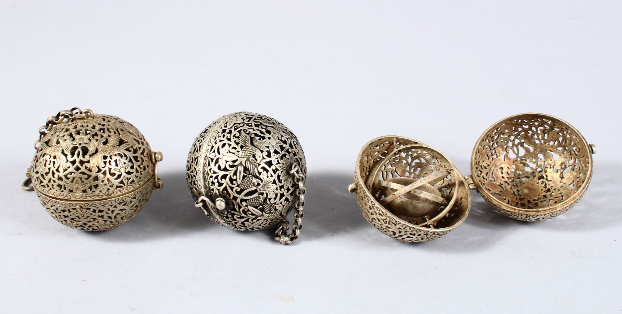 THREE CHINESE WHITE METAL PIERCED INCENSE BURNING BALLS, carved with phoenix amongst lotus, 6cm