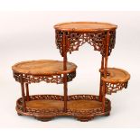 A 19TH CENTURY CHINESE CARVED HARDWOOD THREE TIER STAND, with varying level shelves, with carved and