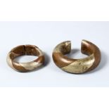 A PAIR OF EARLY MIDDLE EASTERN COPPER SILVER MOUNTED BANGLES, 7CM & 9CM WIDE. (2)